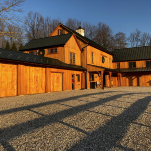 Gravel driveway that leads to a wooden farmhouse.