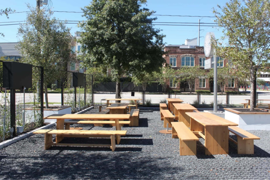 an eco-friendly park design that uses permeable pavers and wood tables