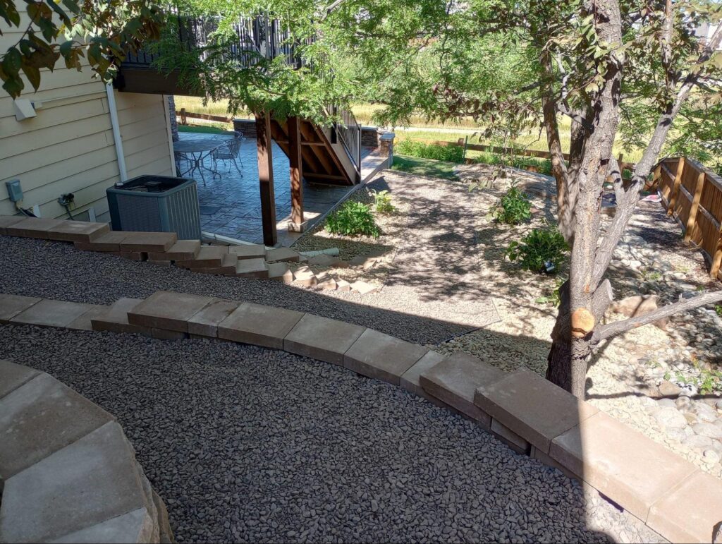 an image of a gravel walkway travels around a house and under a deck