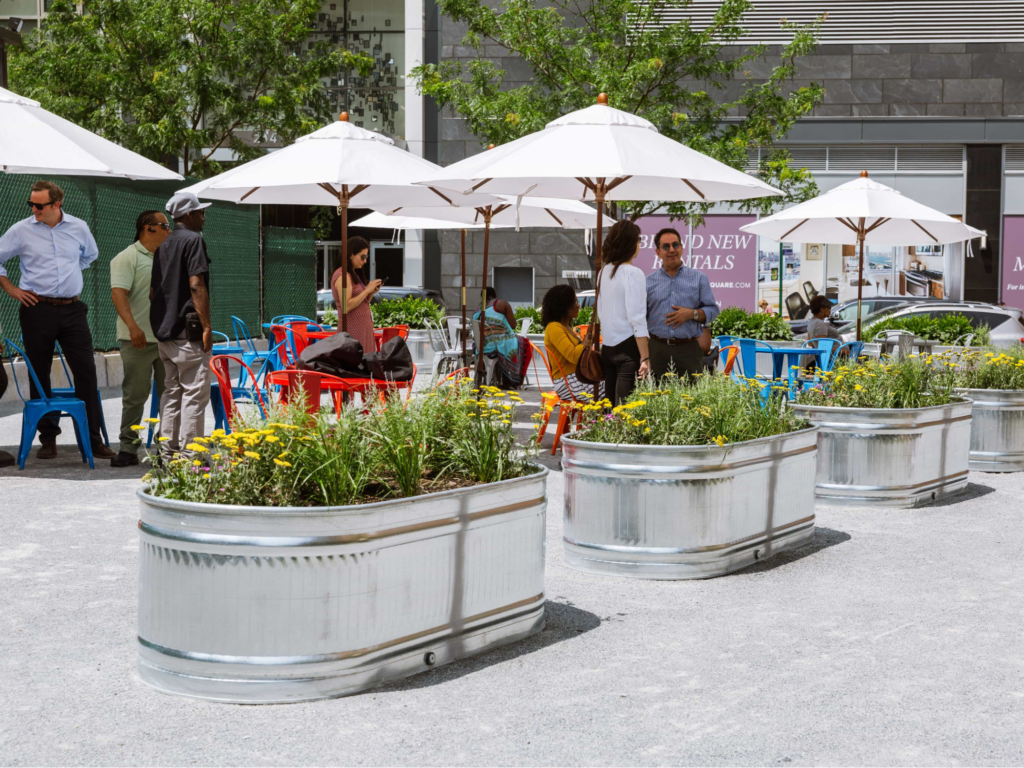 an eco-friendly community hub with tables, umbrellas and flower pots