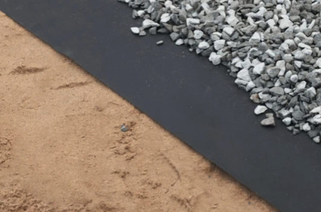 Gravel layered over geotextile fabric and soil.