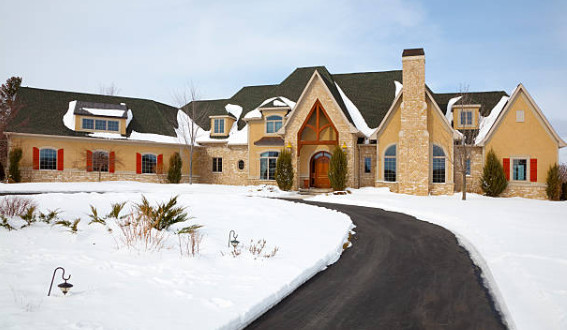 A large house with a snow-covered yard and a heated driveway for easy winter access.