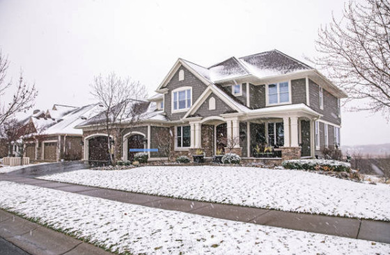 A snowy lawn surrounding a clear, melted heated driveway.