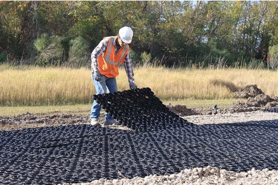 A worker installs TrueGrid permeable paver system, addressing the growing population strain on groundwater supplies.